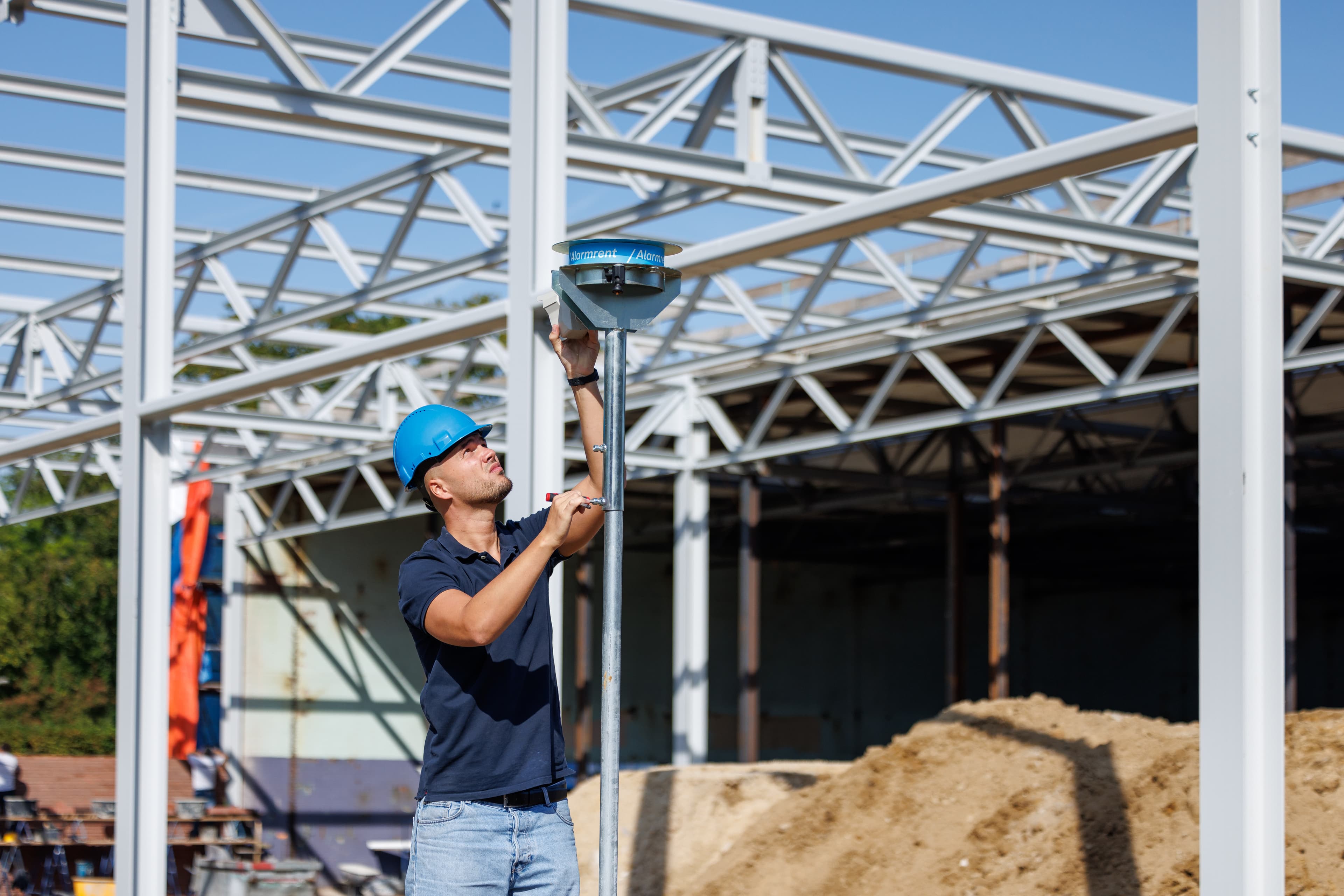 Medewerker van alarmrent installeert bouwplaatsbeveiliging, een vast onderdeel van de bouwplaatskosten.